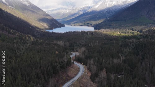 Aerial View of a Car Traveling a Winding Road Through British Columbia's Forest, Mountains, and Lake