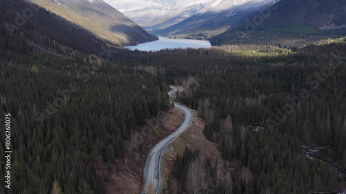Scenic Drive: Car on Winding Mountain Road Towards a Lake Through British Columbia's Forest