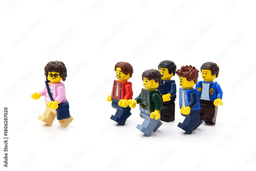 Naklejka premium Many lego minifigures in group are walking behind a girl or woman isolated on white. Editorial illustrative image of popular children plastic constructor.