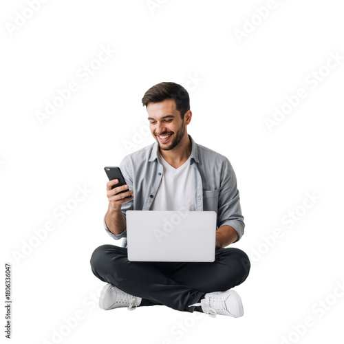 oyful Tech User Smiling at Phone: Young Man in Casual Grey Shirt Balances Laptop on Lap While Delighted by Smartphone, Symbolizing Modern Multitasking, Digital Connection, Work-Life Harmony, and Perso