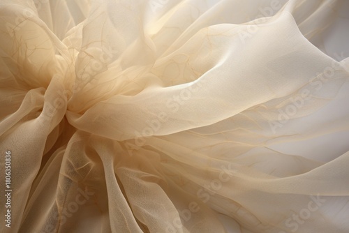 Soft, sheer beige fabric drapes gracefully, creating an abstract texture with delicate folds and subtle light play