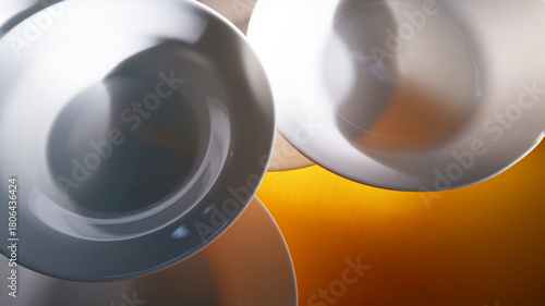 White plate placed on orange background with strong shadow during summer. Abstract tableware background. White plate texture, empty, ceramic, minimal, still-life dishware concept for backdrop, print.