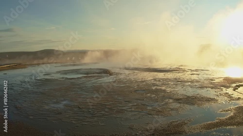 A powerful eruption of the Strokkur Geyser in Iceland's Haukadalur geothermal valley. The footage captures the geyser's column of boiling water and steam against a dramatic sunset sky, highlighting th