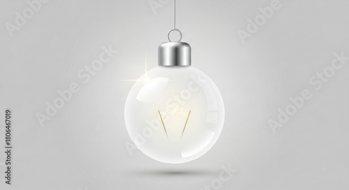 A transparent christmas light bulb ornament hanging from a silver string, casting a soft glow isolated on