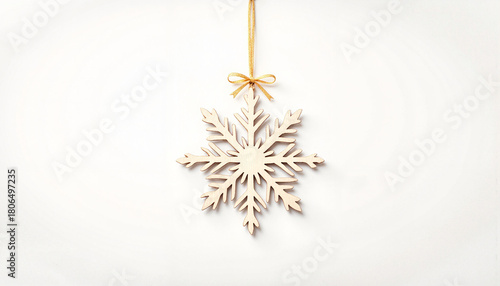 Wooden snowflake ornament with a golden ribbon on a white background, seasonal decoration