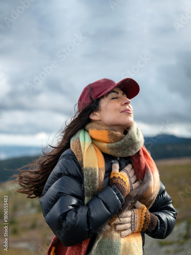 Relaxed woman breathing fresh air in the autumn mountain  and making breathing exercises 