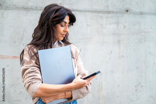 Beautiful young woman using laptop and phone outdoor