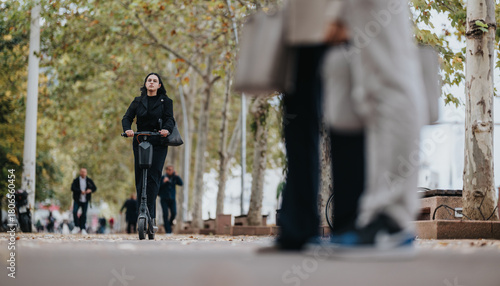 Εκτύπωση καμβά A focused woman on an electric scooter travels down a tree-lined urban street as pedestrians move in the background, capturing everyday city life and active commuting in a calm outdoor scene