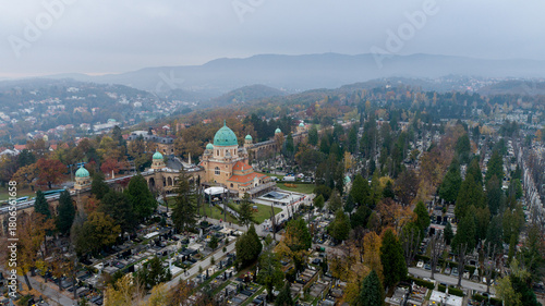 Aerial view of Mirogoj Cemetery's neo-Byzantine domes rise serenely above the autumnal trees, a place of peace and remembrance amidst a misty landscape, Zagreb, Croatia.