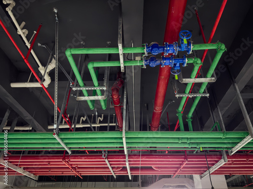 Intricate Network of Color-Coded Industrial Pipes Against a Modern Ceiling Design