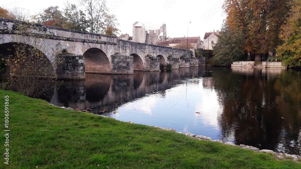 Fototapeta premium Vieux pont de pierre sur le Loing et vue sur la tour de Ganne à Grez-sur-Loing en Seine-et-Marne, France, Europe