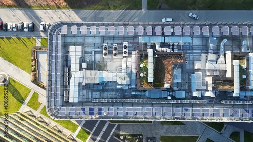 Modern energy-efficient office rooftop showcasing intricate ventilation systems, solar panels, and utilities, captured with a smooth aerial dolly movement emphasizing sustainable architecture