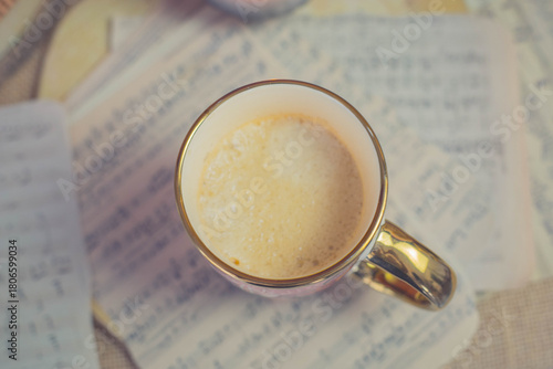 Warm latte in floral cup with candlelight and knitted textures, cozy autumn mood