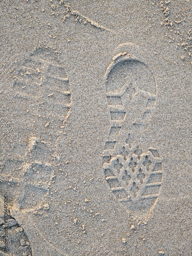 Footprints in soft sand along a beach at sunset reveal a journey by the shore