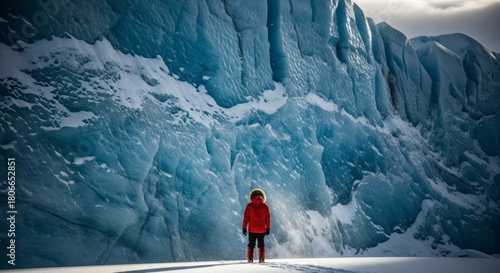 Lone Explorer in Red Parka Facing a Massive Blue Glacier Wall With Drifting Snow and Cinematic Hyper-Realistic Lighting
