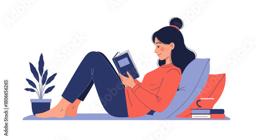 Young woman relaxing comfortably on the floor with pillows while reading an interesting book and enjoying a quiet moment at home.