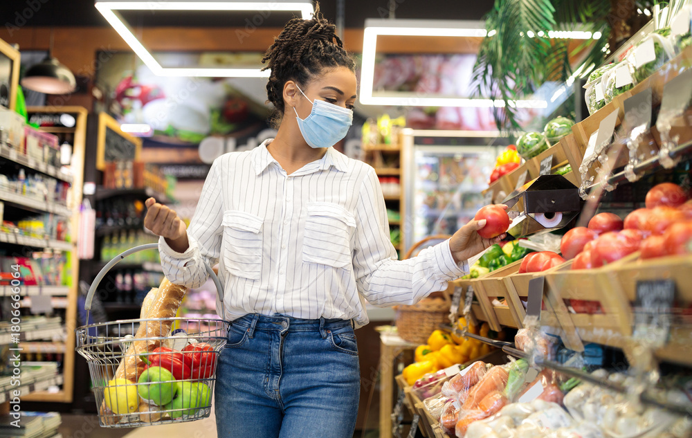 Obraz premium Grocery Shopping. African American Woman Choosing Fresh Vegetables In Supermarket, Walking With Basket Full Of Food Along Shelves In Store Aisle. Groceries Shop Sales And Discounts Concept