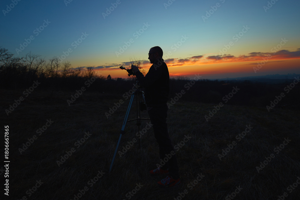 Fototapeta premium Amateur astronomer using telescope for watching stars, Moon, planets and other celestial objects from a field in nature.
