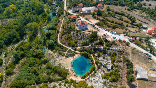 Aerial view of the striking turquoise eye of the Cetina River spring nestled among the rugged, sun-drenched Croatian landscape, Knin, Sibenik-Knin County, Croatia.