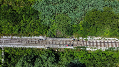 Aerial view of a railway track after a derailment through a vibrant green landscape, with people walking along the tracks, Velika Ludina, Sisacko-moslavacka zupanija, Croatia.
