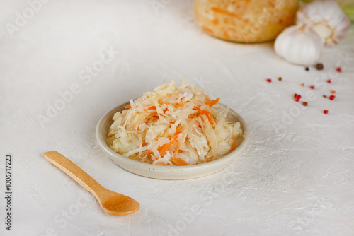 Fresh pickled cabbage, sauerkraut with carrot in a plate with wooden spoon on a table. Healthy, probiotic food.