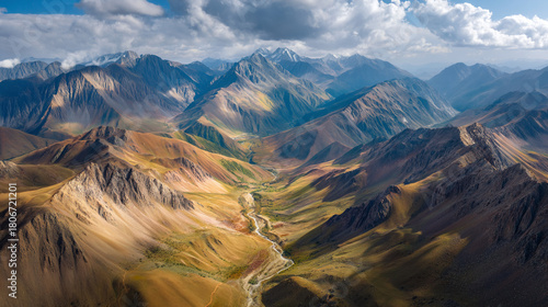Aerial view of a valley with a winding river surrounded by mountains under a cloudy sky
