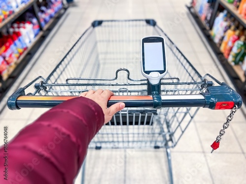 Fotografi A hand-held bar code scanner on a shopping cart in a large supermarket