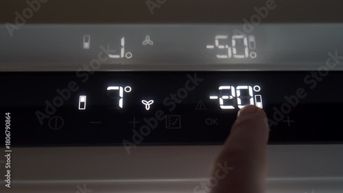 A finger presses the plastic temperature button on the refrigerator's control panel. The capacitive or physical button makes a quiet, soft clicking sound upon being touched.