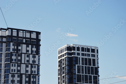 Two modern stylish high-rise residential apartment buildings with gray and white decorative elements of the facade. Urban architecture.