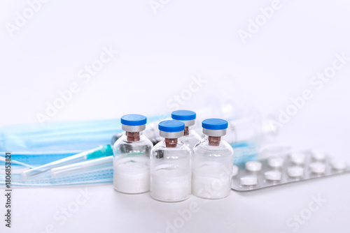 A still life of medical syringes and medication vials. Disposable syringes, medical masks, and fever pills. Supplies for injections and virus protection. 