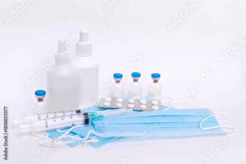 A still life of medical syringes and medication vials. Disposable syringes, medical masks, and fever pills. Supplies for injections and virus protection. 