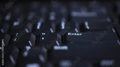 Enter key on dark keyboard — technology background with shallow depth of field