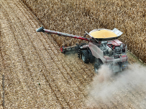 Arial view of a combine moving through a corn field harvesting corn