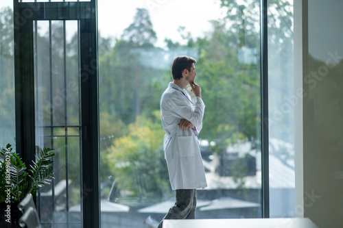 Male doctor looking thoughtfully out of window