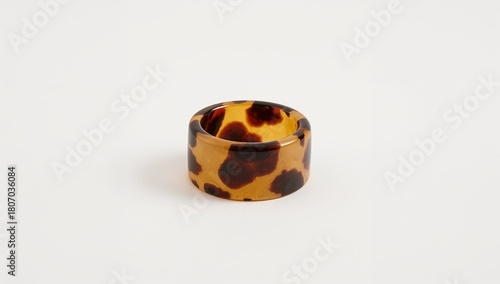 Tortoiseshell patterned resin ring presenting warm tones on plain white background