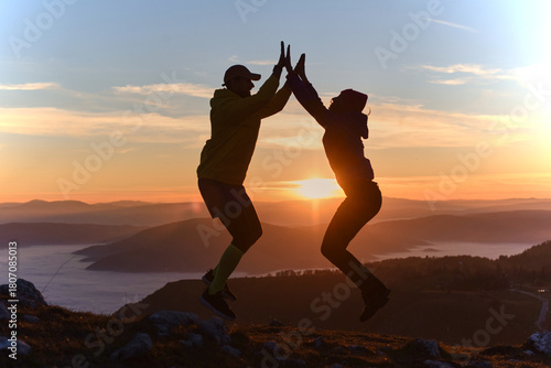Foto Jumping silhouettes celebrate sunset on mountain peak with friends in beautiful