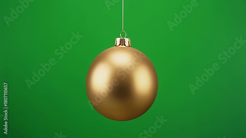 Golden christmas ornament hanging and swinging on a green screen background