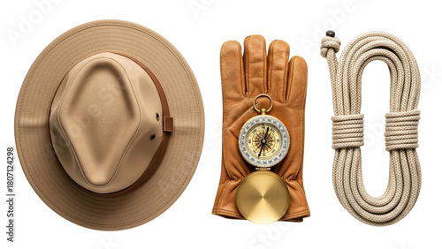 Flat lay arrangement of a textured straw hat brown leather glove and coiled rope with vintage compass on a stark black background symbolizing