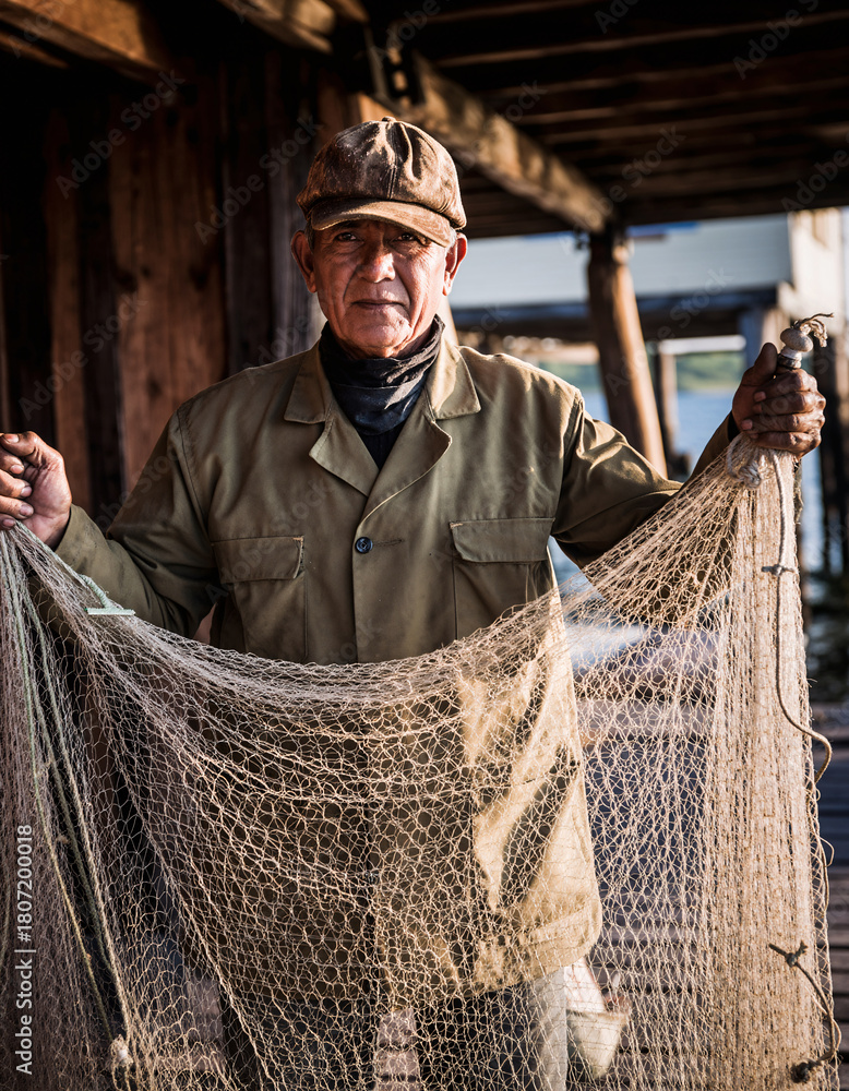 Fototapeta premium Old fisherman holding net under warm morning light
