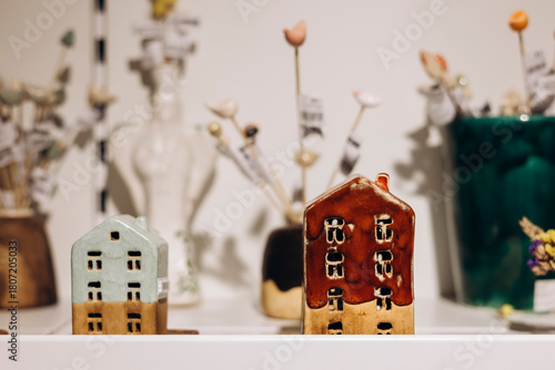 Ceramic candle holders in the shape of houses displayed on a store shelf.