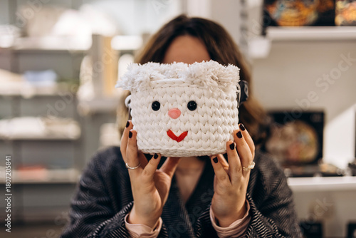 Woman holding smiling acorn-shaped crochet basket in store.