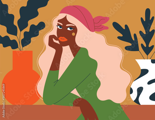 Stylish woman with long hair and headscarf surrounded by plants in a cozy space