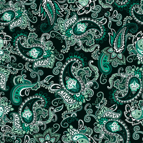Seamless green and black paisley pattern on a dark forest green background. Traditional batik flower motif for textile fabrics.
