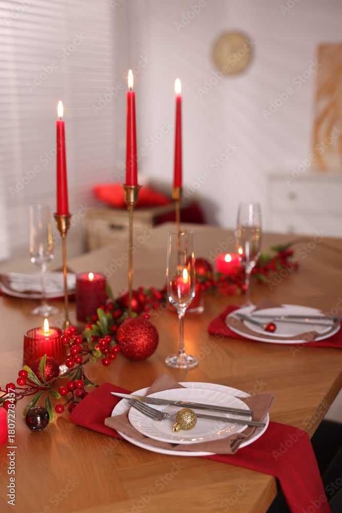 Obraz premium Stylish Christmas table setting with plates, glasses and burning candles in room, closeup