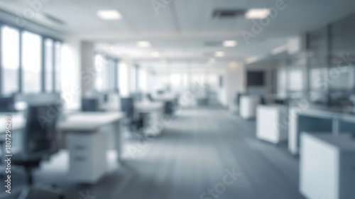 Blurry view of an open office space with desks chairs and large windows in a modern building