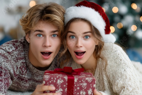 Excited couple receiving christmas gift with surprise