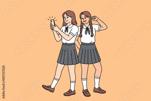 Two young girls in school uniforms take a selfie together, smiling and posing.