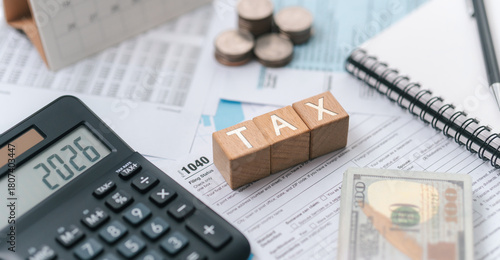 Tax planning concept for 2026. Wooden blocks with the word tax. Calculator on phone. Interest, Financial calculations, Tax law, Tax payment, Government taxes and budget planning.