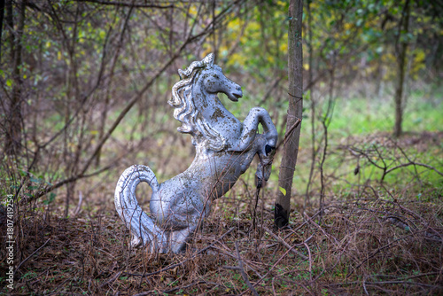 Wallpaper Mural Weathered Silver Horse Statue Standing on Its Hind Legs Among Dry Grass, Twigs, and Thin Branches, Set Within an Overgrown Outdoor Area with Soft Greenery in the Background Torontodigital.ca