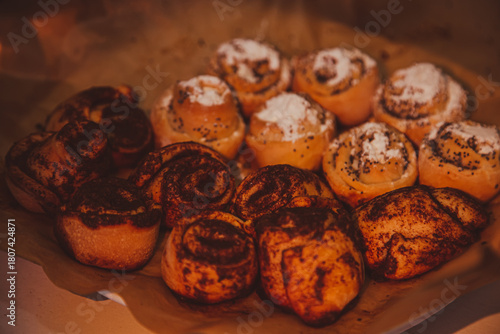 Tasty cinnamon rolls with cream on parchment paper, above view